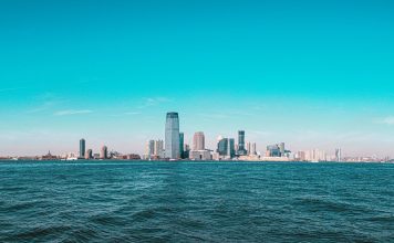 Cosas Gratis Que Hacer en Jersey City en 2026: Guía Completa de Aventuras Sin Gastar un Dólar Panoramic view of Manhattan skyline with modern skyscrapers under a clear blue sky.
