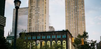 A vibrant intersection in Jersey City with towering skyscrapers and a historic building.