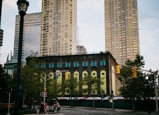 A vibrant intersection in Jersey City with towering skyscrapers and a historic building.