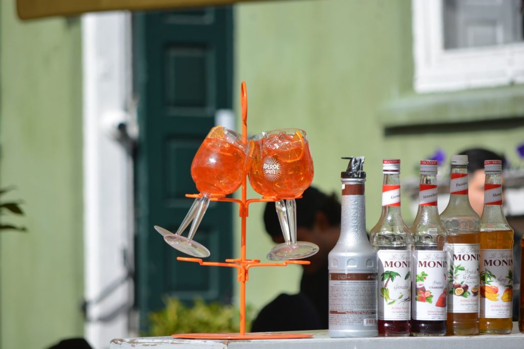 Colorful Aperol Spritz and Monin syrups on display outdoors, perfect for summer cocktails.