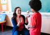 HCST Teacher Wins Hudson County Honor for Second Straight Year A teacher holding an apple and a student holding a trophy in a classroom setting.
