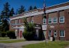 A classic brick schoolhouse in Redfield, NY with a U.S. Post Office, capturing a sunny day.