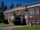 A classic brick schoolhouse in Redfield, NY with a U.S. Post Office, capturing a sunny day.
