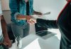 Two people shaking hands over a desk signifies a business agreement or partnership.