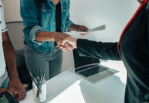 Two people shaking hands over a desk signifies a business agreement or partnership.