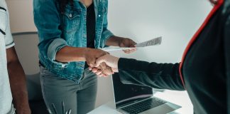 Two people shaking hands over a desk signifies a business agreement or partnership.