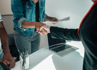 Two people shaking hands over a desk signifies a business agreement or partnership.