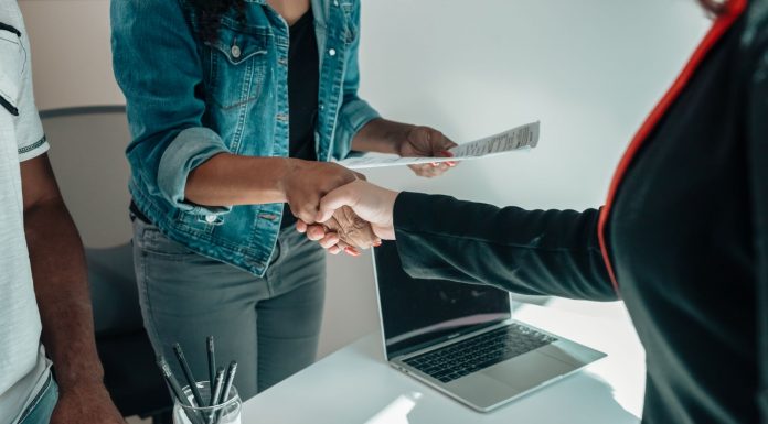 Two people shaking hands over a desk signifies a business agreement or partnership.