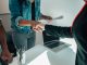 Two people shaking hands over a desk signifies a business agreement or partnership.