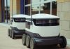 Hoboken Approves Delivery Robot Pilot Program Two autonomous delivery robots positioned outside a modern building, showcasing innovation in robotics and mobility.