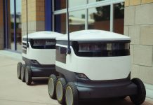 Hoboken Approves Delivery Robot Pilot Program Two autonomous delivery robots positioned outside a modern building, showcasing innovation in robotics and mobility.