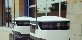 Two autonomous delivery robots positioned outside a modern building, showcasing innovation in robotics and mobility.