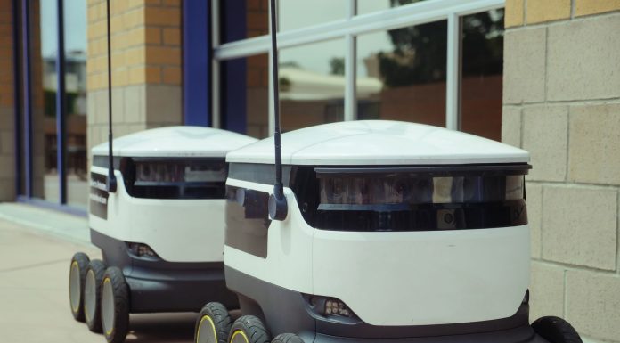 Two autonomous delivery robots positioned outside a modern building, showcasing innovation in robotics and mobility.