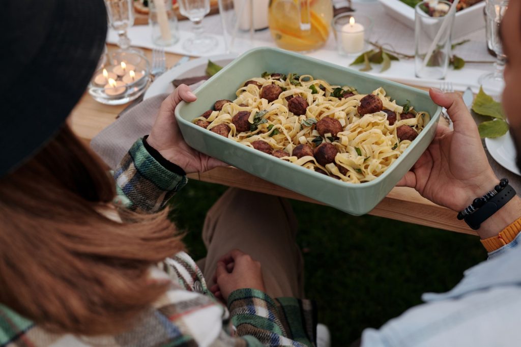 Aerial view of a delicious pasta and meatball dish being served at a cozy outdoor gathering.