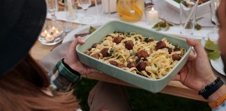 Aerial view of a delicious pasta and meatball dish being served at a cozy outdoor gathering.