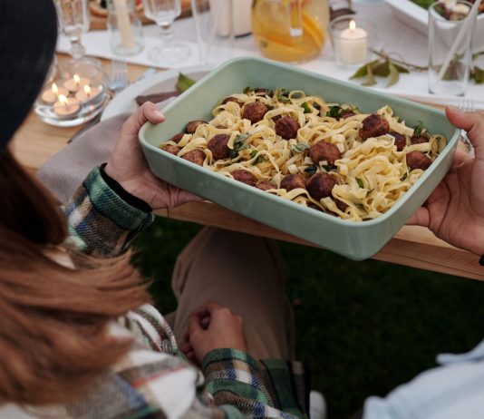 Aerial view of a delicious pasta and meatball dish being served at a cozy outdoor gathering.