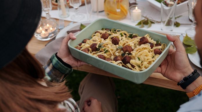 Aerial view of a delicious pasta and meatball dish being served at a cozy outdoor gathering.