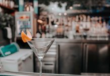 Hoboken’s The LOLA Debuts Giant Martini Towers for Group Nights Out Martini glass with orange peel on bar counter in chic cocktail lounge.