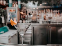 Martini glass with orange peel on bar counter in chic cocktail lounge.
