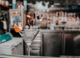 Martini glass with orange peel on bar counter in chic cocktail lounge.