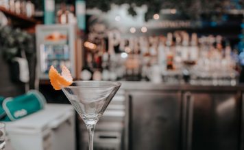 Martini glass with orange peel on bar counter in chic cocktail lounge.