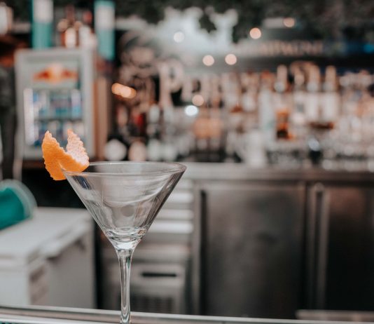 Martini glass with orange peel on bar counter in chic cocktail lounge.