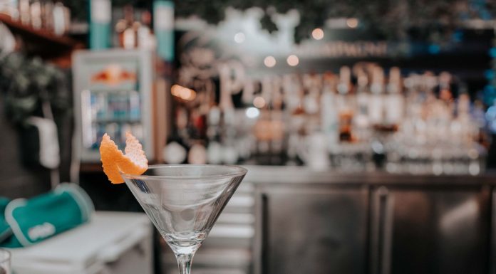 Martini glass with orange peel on bar counter in chic cocktail lounge.