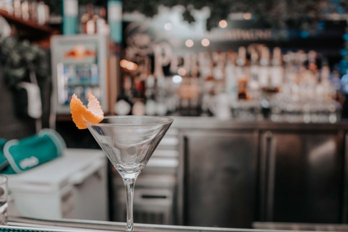 Martini glass with orange peel on bar counter in chic cocktail lounge.