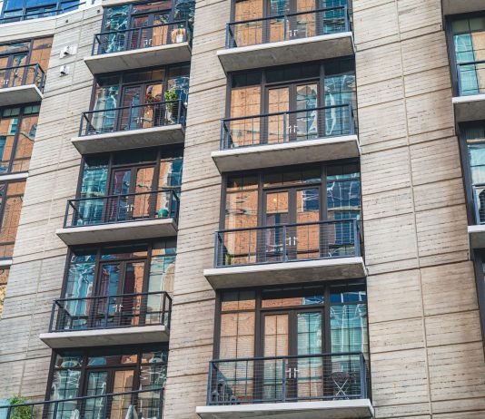 Contemporary apartment building exterior with concrete facade and glass balconies.