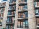 Contemporary apartment building exterior with concrete facade and glass balconies.
