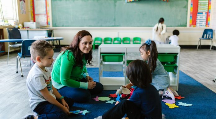 Teacher and children engaged in educational activities on a classroom floor.