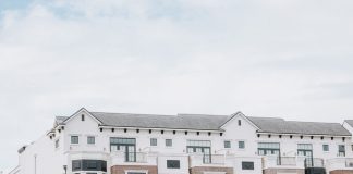 A stylish, multi-story luxury apartment building with a contemporary facade against a clear sky.