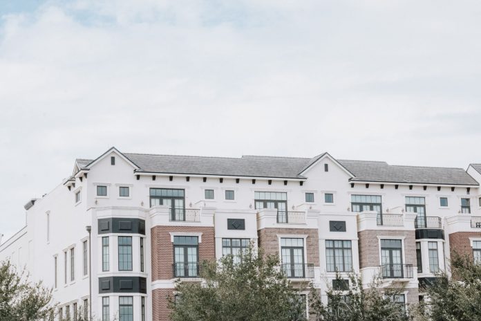 A stylish, multi-story luxury apartment building with a contemporary facade against a clear sky.