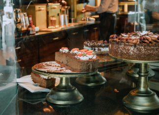 Hybrid Coffee Returns to Jersey City Heights With Torico’s Ice Cream Tempting chocolate cakes with decorations on display in a cozy cafe setting.