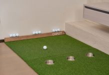Indoor putting green with golf balls and equipment for golf practice at home.