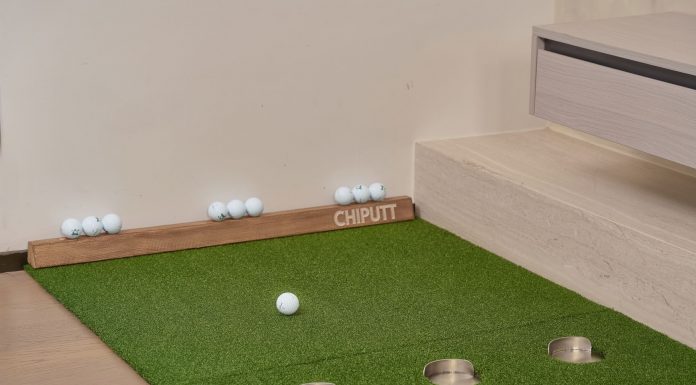 Indoor putting green with golf balls and equipment for golf practice at home.