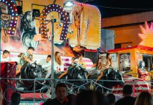 People enjoying a vibrant bull ride at an outdoor funfair at night.