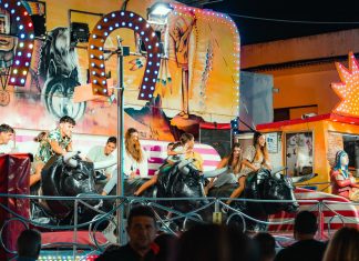 People enjoying a vibrant bull ride at an outdoor funfair at night.