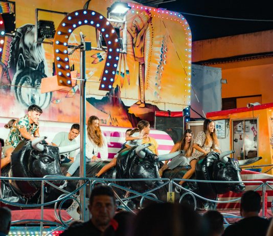 People enjoying a vibrant bull ride at an outdoor funfair at night.