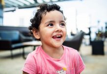 Jersey City 3-Year-Old Gabby Mateo Advances in Toddler of the Year Contest Cheerful young girl with curly hair smiling brightly in an indoor setting, exuding happiness.