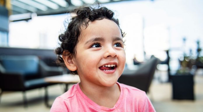 Jersey City 3-Year-Old Gabby Mateo Advances in Toddler of the Year Contest Cheerful young girl with curly hair smiling brightly in an indoor setting, exuding happiness.