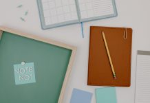 Top view of office supplies including a planner, pencil, and vote message for creative workspaces.