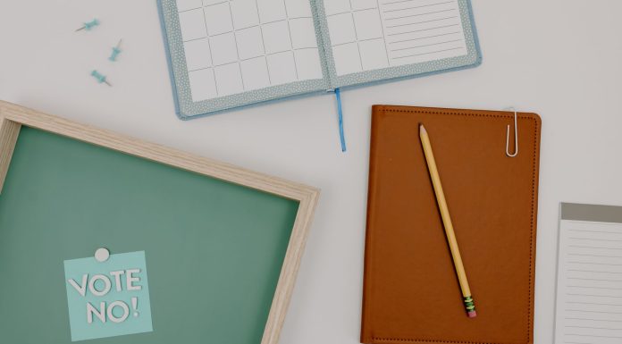 Top view of office supplies including a planner, pencil, and vote message for creative workspaces.