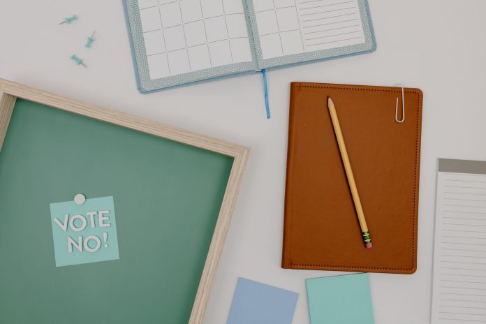jersey-city-board-to-vote-on-new-mcnair-infinity-a Top view of office supplies including a planner, pencil, and vote message for creative workspaces.