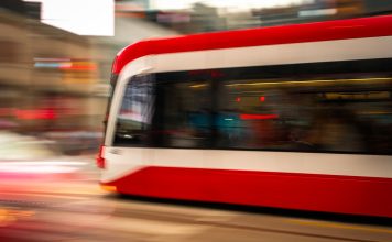 Blurred motion photo of a red tram speeding through city streets, capturing urban energy.