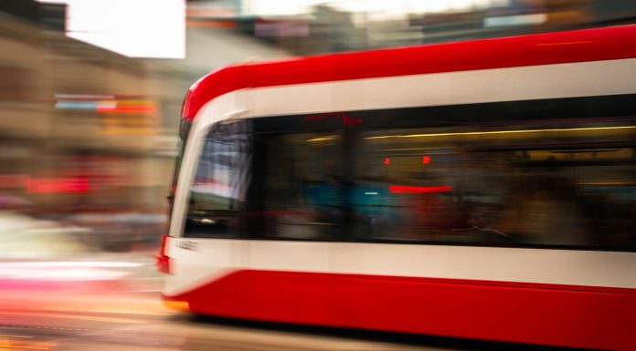 Jersey City BRT Community Meeting Set for Sept. 23 Blurred motion photo of a red tram speeding through city streets, capturing urban energy.