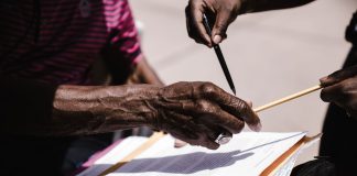 Close-up of hands exchanging documents with pens outdoors. Business agreement concept.