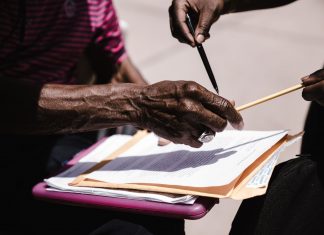 Close-up of hands exchanging documents with pens outdoors. Business agreement concept.