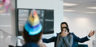 A surprised woman at an office party celebration with colleagues.