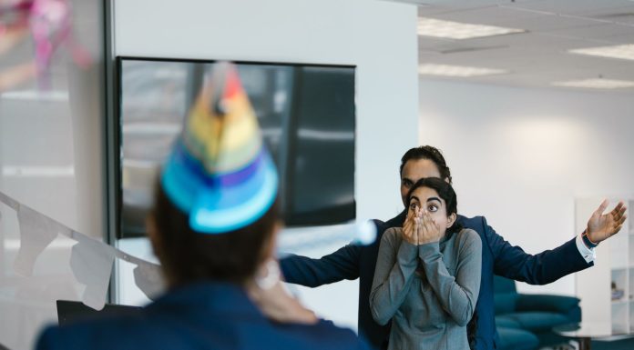 A surprised woman at an office party celebration with colleagues.